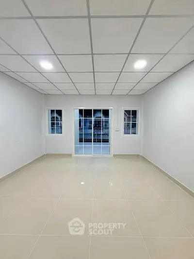 Spacious empty room with tiled floor and large windows, ideal for customization.
