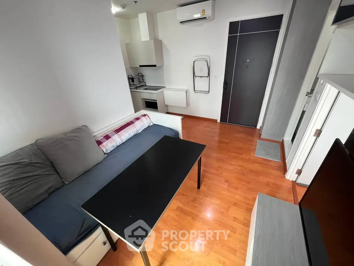 Modern apartment living room with cozy sofa and sleek kitchen area, perfect for urban living.