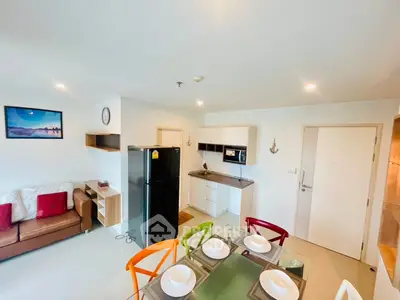 Modern open-plan living room and kitchen with colorful chairs and sleek appliances.