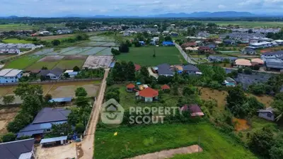 Aerial view of suburban landscape with houses, fields, and distant mountains.