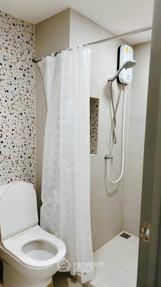 Modern bathroom with shower and toilet featuring stylish tile design.