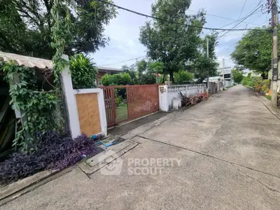 Charming residential street with lush greenery and gated entrance, perfect for serene living.