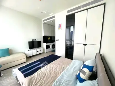 Modern studio apartment with sleek design, featuring a cozy bed, compact kitchen, and stylish decor.