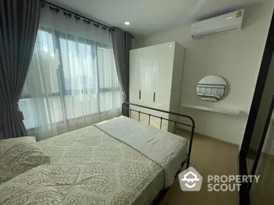 Cozy bedroom with modern decor, large window, and air conditioning unit in a stylish apartment.