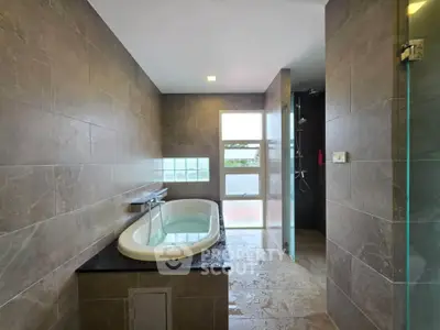 Luxurious bathroom with elegant bathtub and modern shower area, featuring sleek tile design and natural lighting.