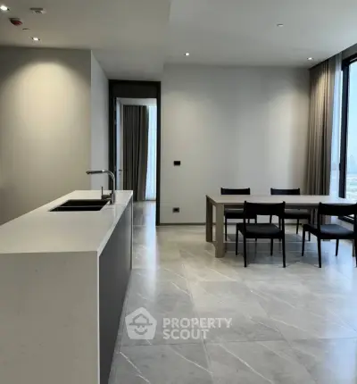 Modern open-plan kitchen and dining area with sleek design and large windows.