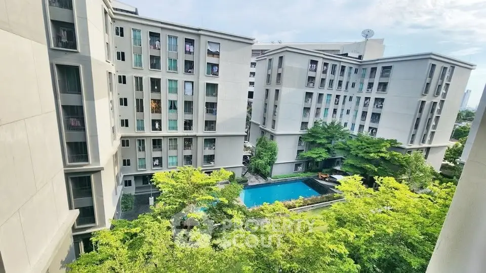 Modern apartment complex with lush greenery and inviting pool view.