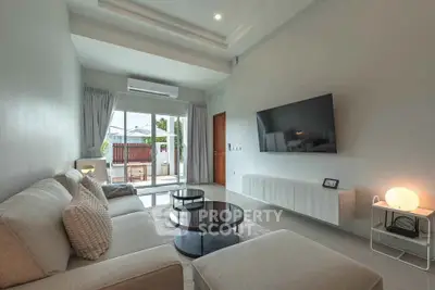 Modern living room with sleek design, featuring a large sofa, wall-mounted TV, and natural light.