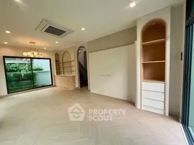 Spacious modern living room with built-in shelves and large window view.