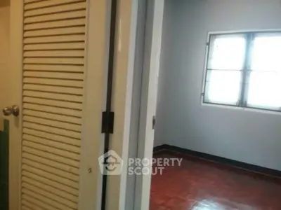 Spacious room with wooden flooring and ample natural light through large window.