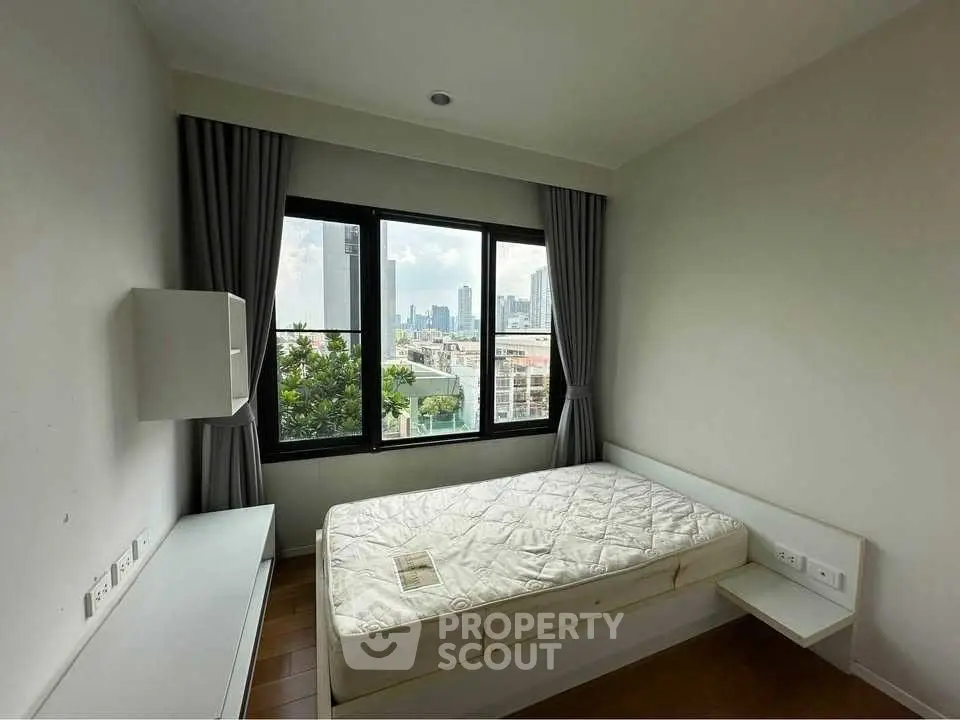 Cozy bedroom with city view, featuring a comfortable bed and large window for natural light.