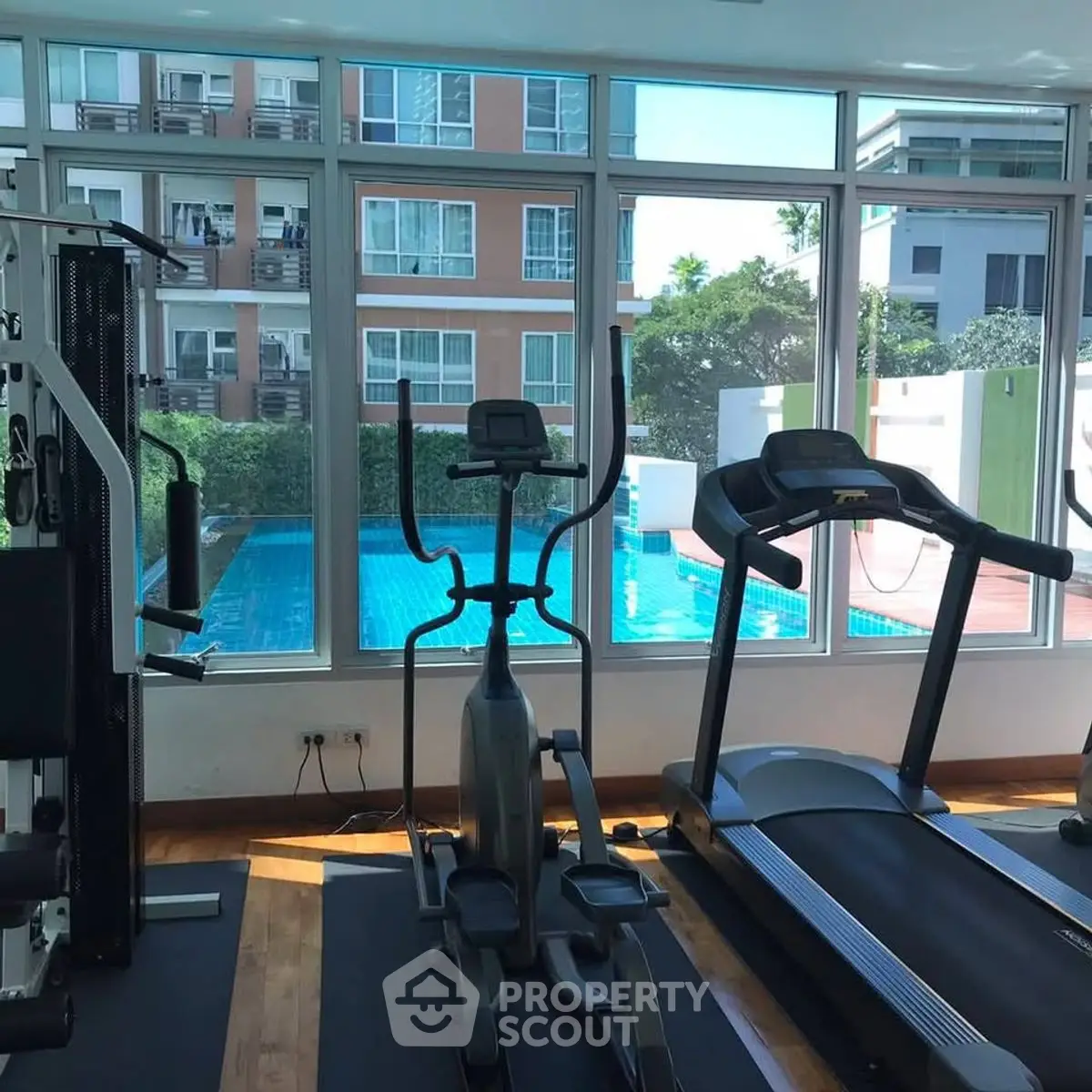 Modern gym with pool view in luxury apartment complex