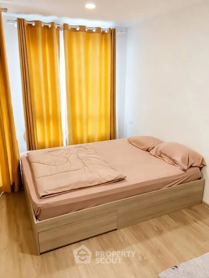 Cozy bedroom with wooden flooring and bright curtains, perfect for relaxation.