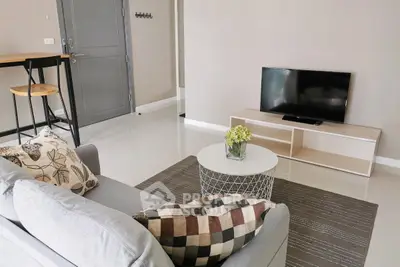 Modern living room with cozy sofa and flat-screen TV, perfect for relaxation.