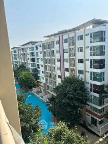 Stunning view of modern apartment complex with pool and lush greenery.