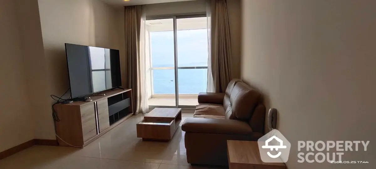 Spacious living room with modern furniture, large windows offering abundant natural light and a serene sea view, perfect for relaxation and entertainment.