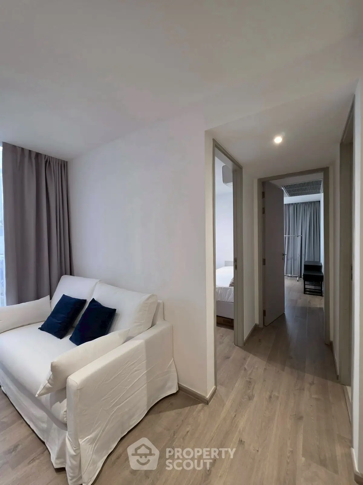 Modern apartment interior with cozy living area and hallway leading to bedrooms.