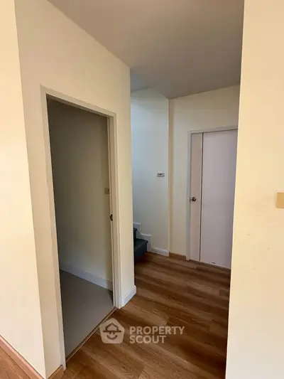 Spacious hallway with wooden flooring and modern doors in a stylish home.