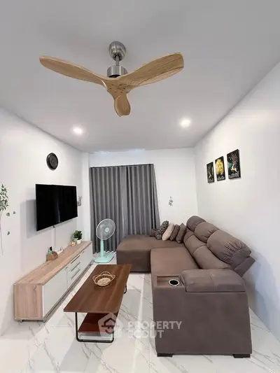 Modern living room with stylish ceiling fan, cozy sectional sofa, and sleek entertainment unit.