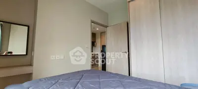 Cozy bedroom with modern decor and view into a sleek kitchen area.