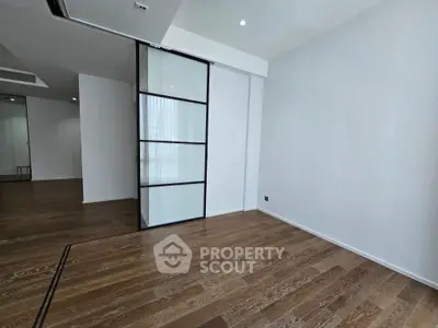 Spacious modern interior with wooden flooring and glass partition, ideal for versatile living space.