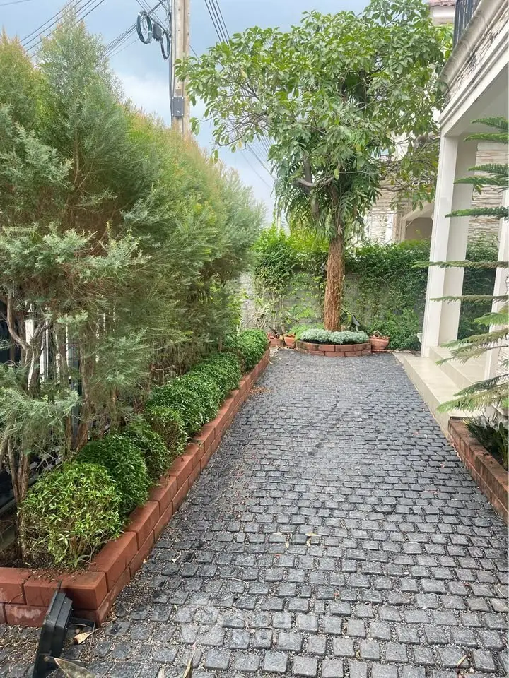 Charming garden pathway with lush greenery and brick-lined borders in a serene residential setting.