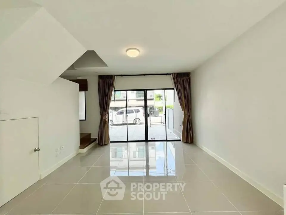 Spacious modern living room with large windows and glossy tiled floors