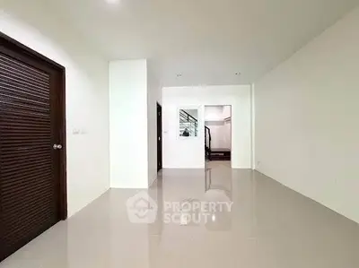 Spacious modern interior with glossy tiled floors and wooden door, ideal for customization.