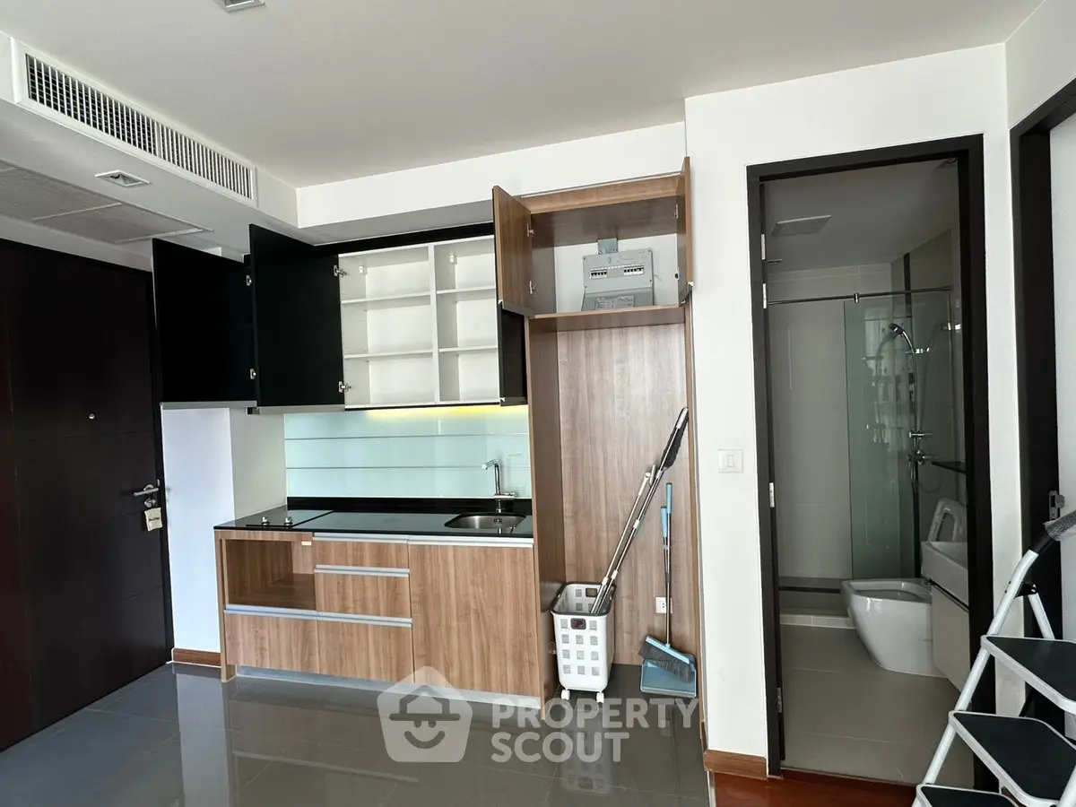 Modern compact kitchen with sleek cabinets and adjacent bathroom in a stylish apartment.