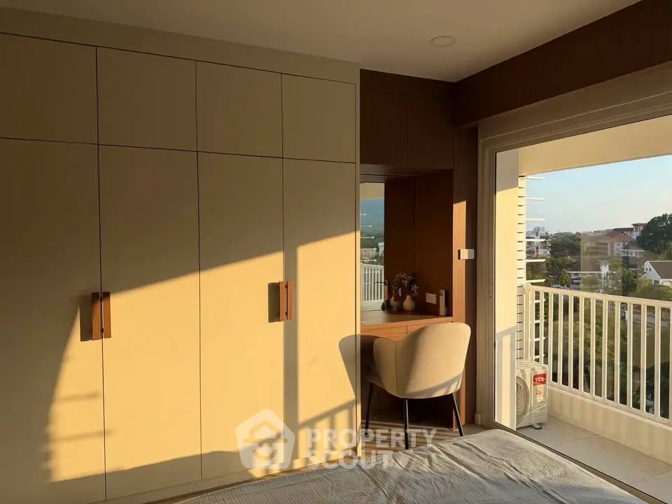 Sunlit bedroom with built-in wardrobe and balcony view, perfect for relaxation.