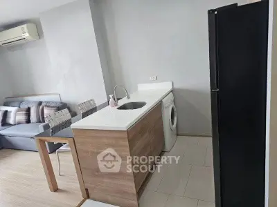 Modern apartment interior with compact kitchen and living area featuring washing machine and sleek design.