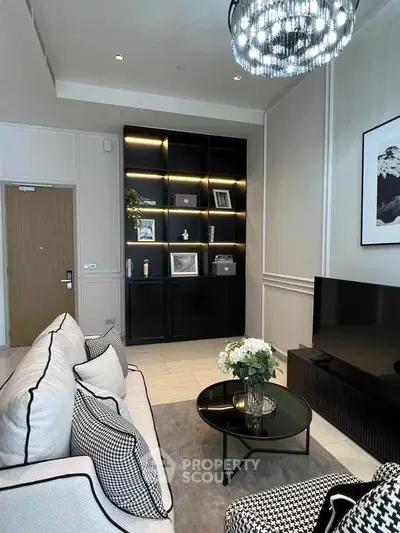 Elegant living room with modern decor, black shelving, and stylish chandelier.