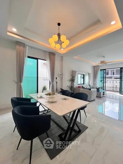 Elegant modern living room with dining area, featuring stylish lighting and open layout.