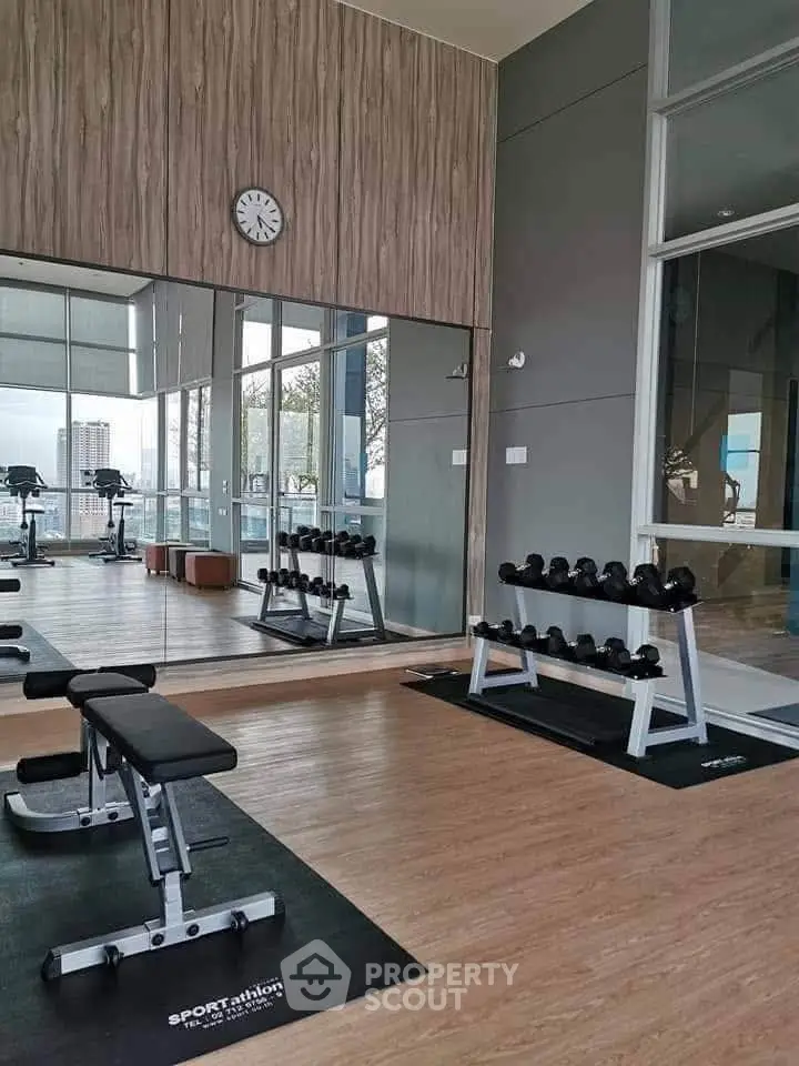 Modern gym with mirrored walls and city view in luxury apartment building.