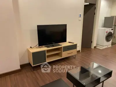Modern living room with sleek TV stand and glass coffee table on wooden flooring.