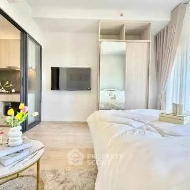 Modern bedroom with stylish decor and natural light, featuring a cozy bed and sleek TV setup.