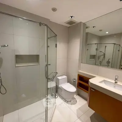 Modern bathroom with glass shower and sleek fixtures in contemporary apartment.