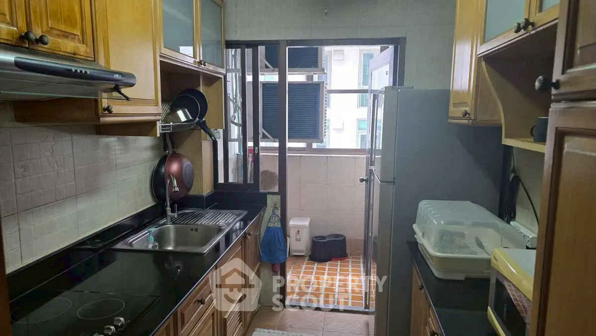 Charming kitchen with wooden cabinets and modern appliances, leading to a small balcony with city views.