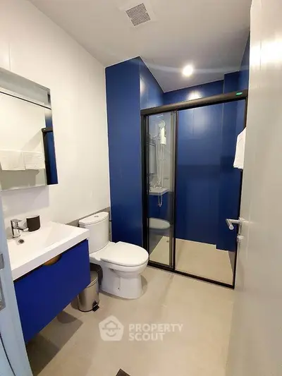 Modern bathroom with blue accents and glass shower enclosure