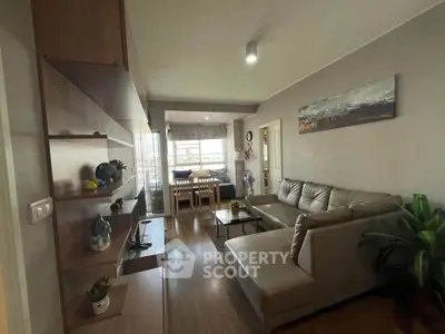 Modern living room with stylish decor and dining area, featuring a cozy sectional sofa and elegant shelving.