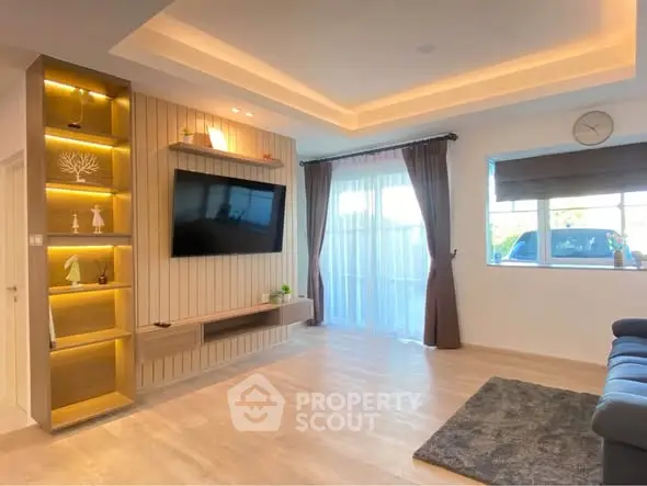 Modern living room with stylish lighting and large window, featuring a wall-mounted TV and cozy seating area.