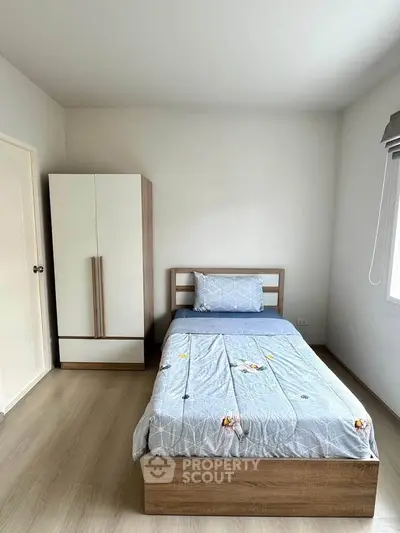 Cozy minimalist bedroom with single bed and wardrobe, perfect for a serene living space.