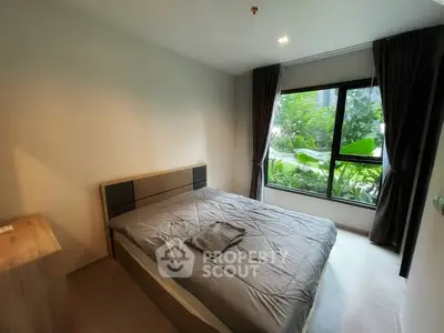 Cozy bedroom with large window overlooking lush greenery, perfect for relaxation and comfort.
