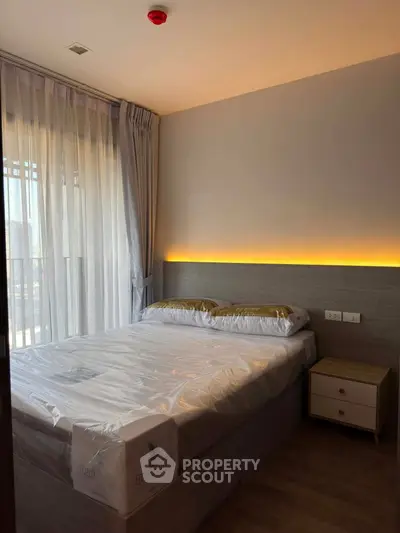 Modern bedroom with ambient lighting and large window in a stylish apartment.