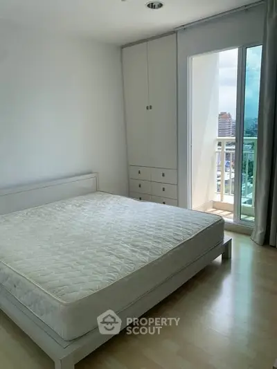 Bright bedroom with large window and balcony access, featuring a minimalist design and ample natural light.