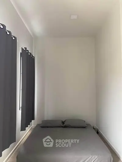 Minimalist bedroom with gray curtains and bedding, showcasing a cozy and simple design.