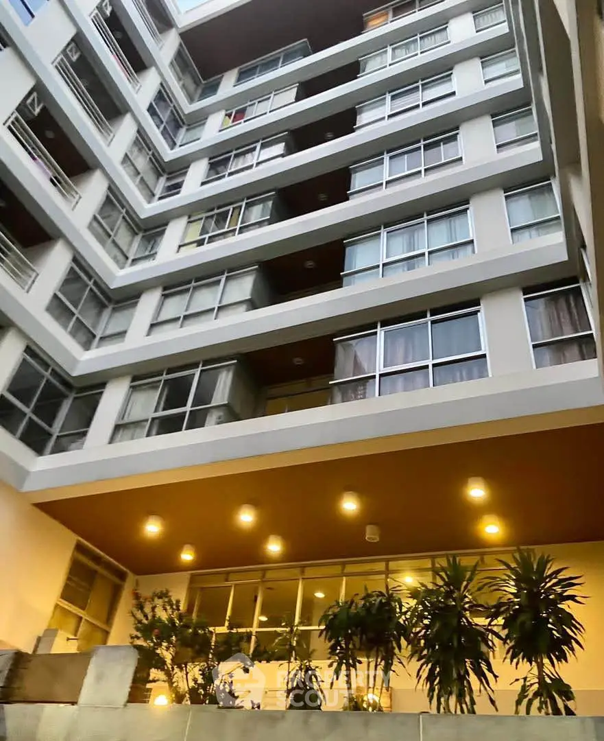 Modern apartment building with illuminated entrance and greenery