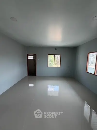 Spacious empty room with large windows and glossy tiled floor, perfect for customization.