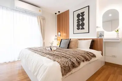 Modern bedroom with stylish decor and natural light, featuring a cozy bed and elegant wall art.