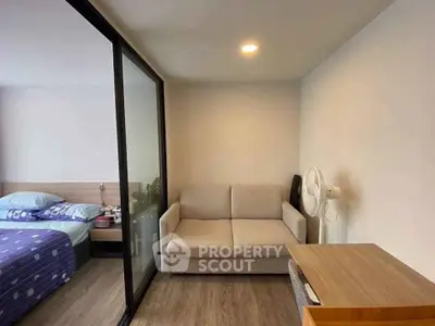 Cozy studio apartment with modern sliding glass partition and comfortable furnishings.